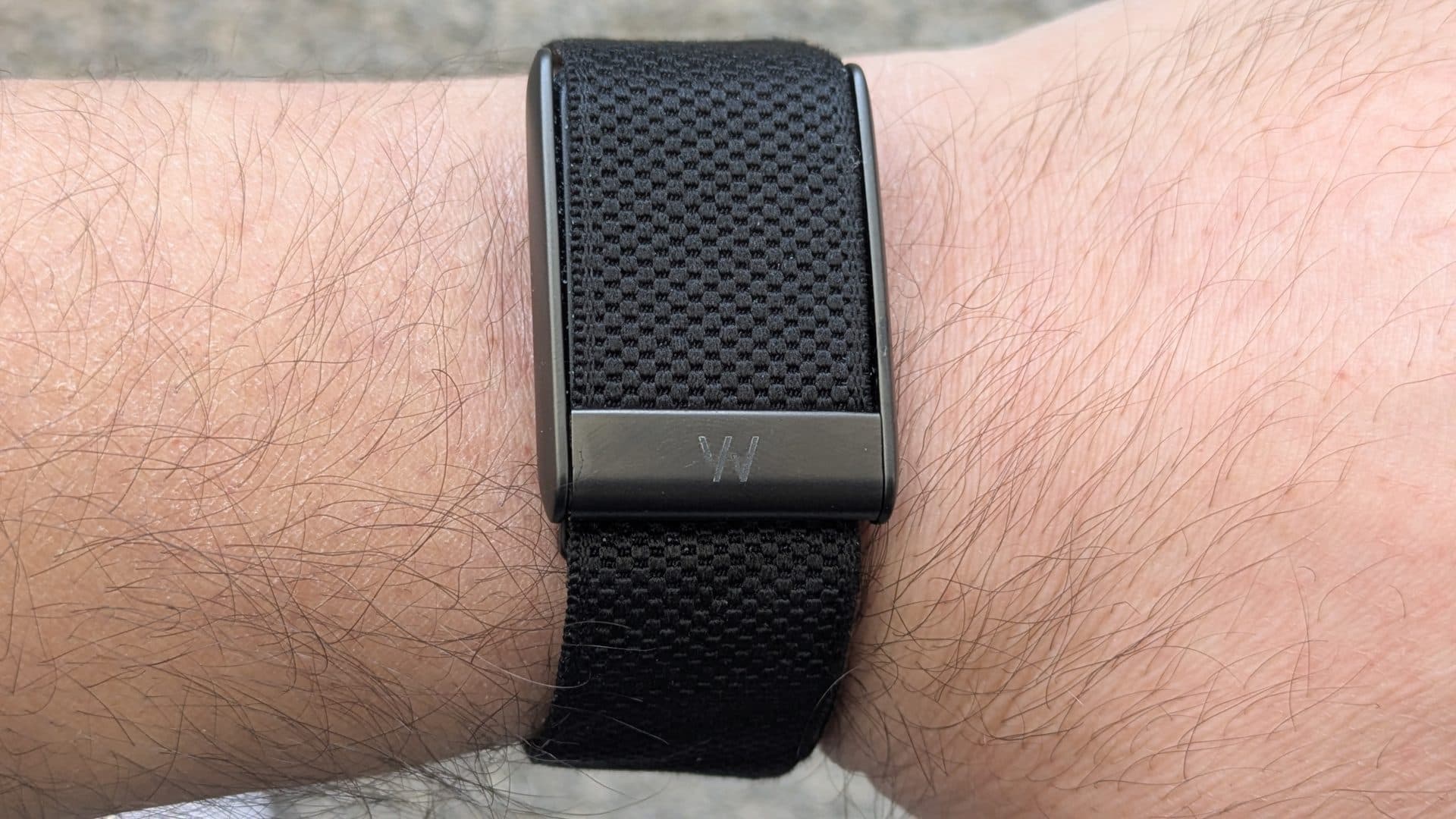 Whoop 5.0 fitness tracker worn on a wrist with a black sensor module and fabric band