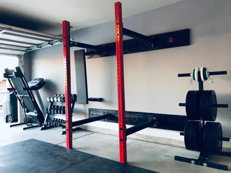 Rogue RML-3WC Fold Back Wall Mount Rack extended in a garage gym with a barbell racked on black rubber flooring