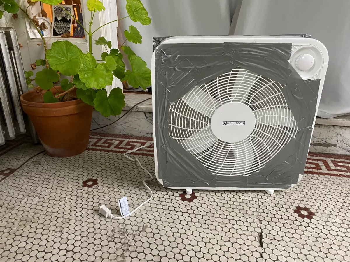 DIY box fan air filter taped to a furnace filter on a wooden floor