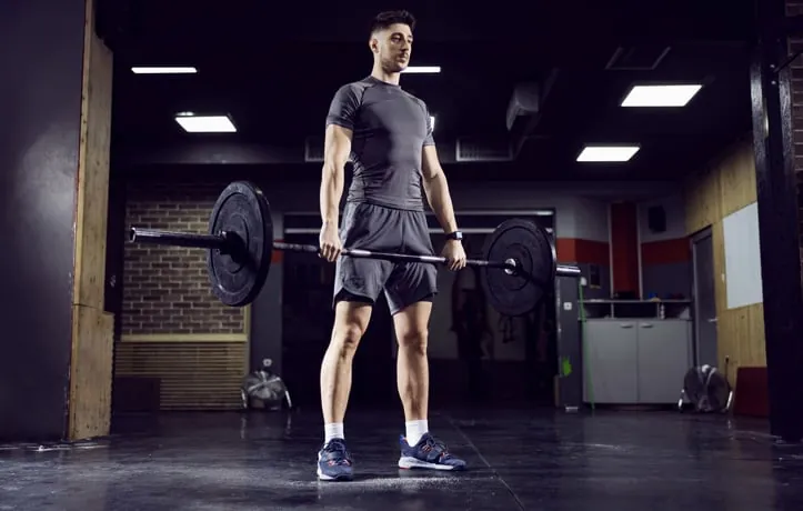 Person performing a dumbbell Romanian deadlift with dumbbells held in front of the thighs