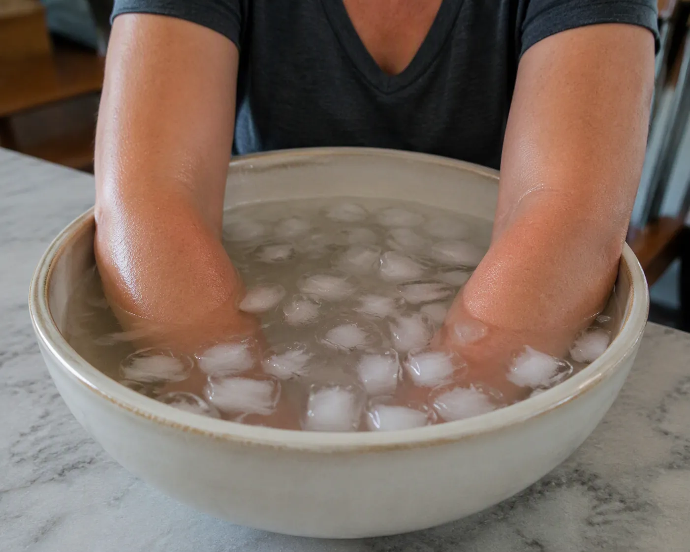 Forearms and elbows submerged in a bowl of ice water for post-workout cooling