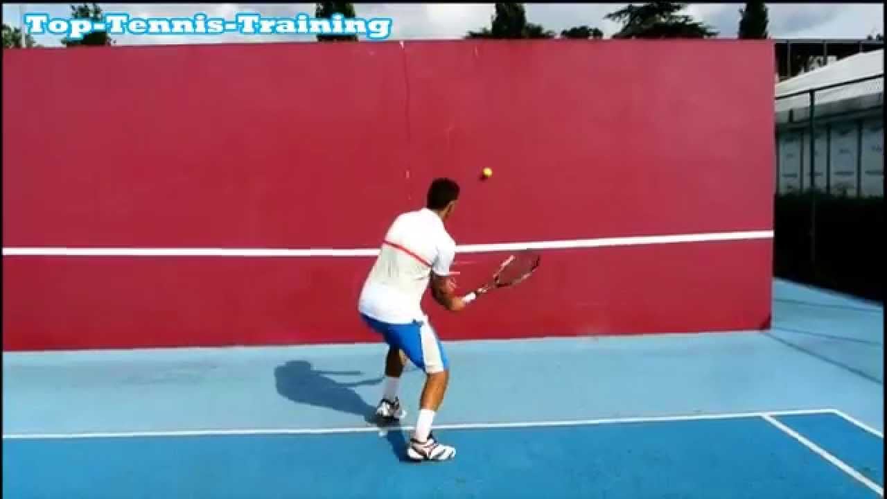 Tennis player practicing forehands against an outdoor backboard