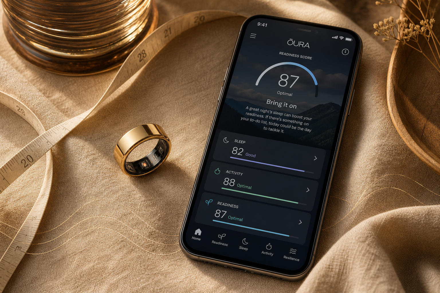 A flat-lay composition with a silver Oura Ring resting on warm linen beside a smartphone displaying the Oura app's Readiness Score dashboard showing Readiness, Sleep, and Activity scores, with a soft fabric measuring tape curving beside the ring and a faint wave line graphic on the surface, lit in warm golden-hour style.