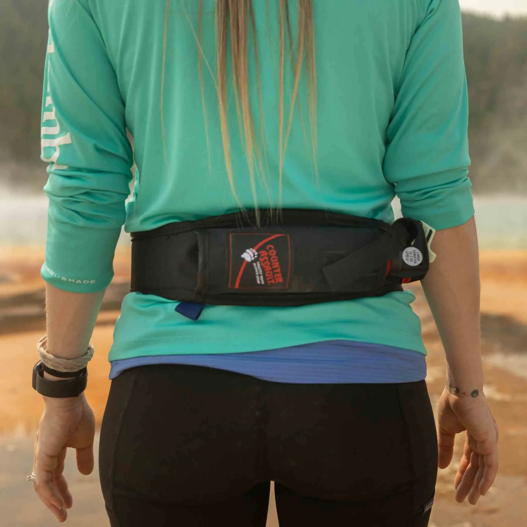 Trail runner carrying bear spray in an accessible hip holster while moving on a dirt path
