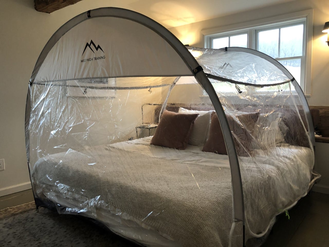 Hypoxic altitude training tent installed over a bed with generator equipment beside the frame