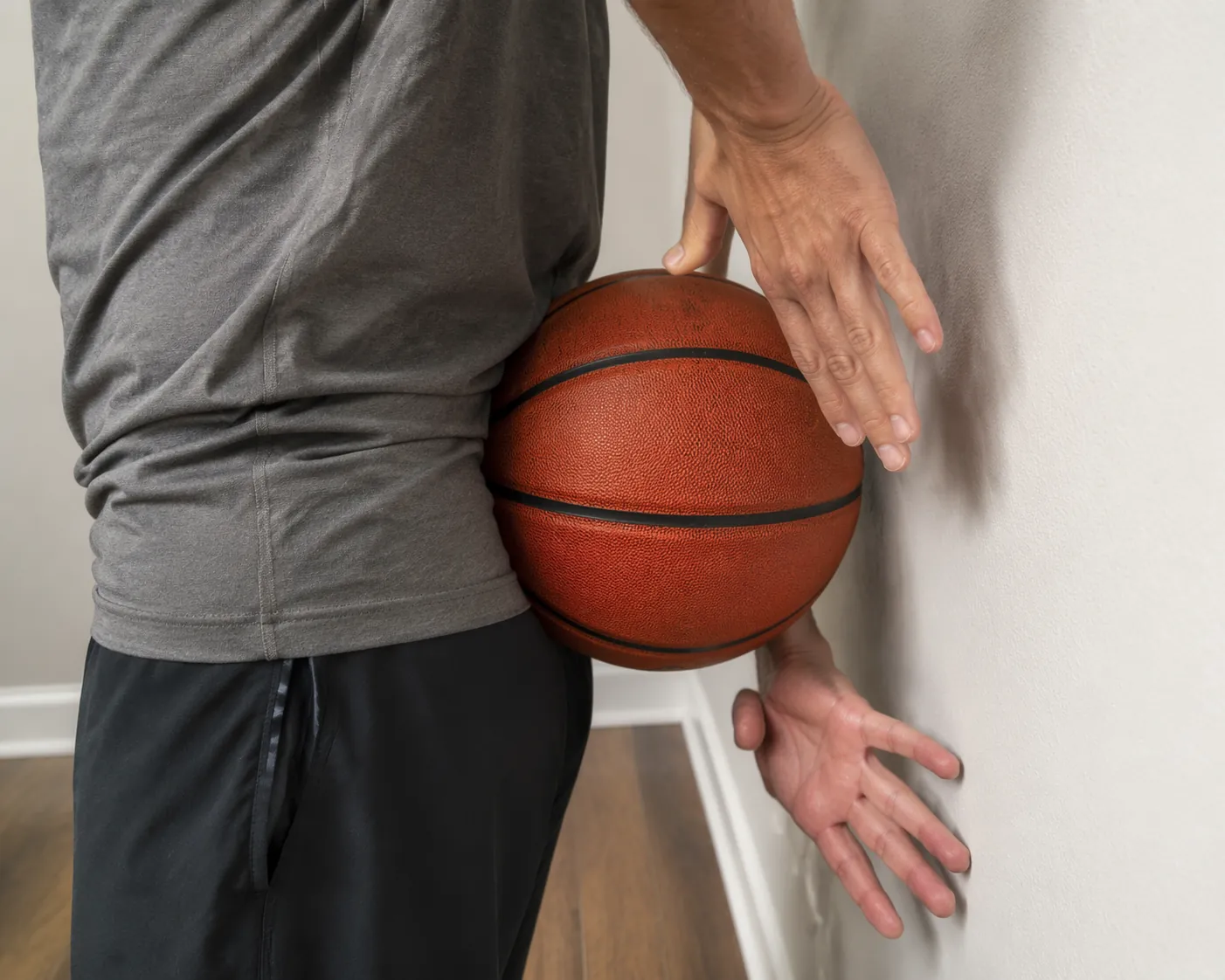 Close-up of a basketball being tapped against a wall from behind the back during a wall-tap drill