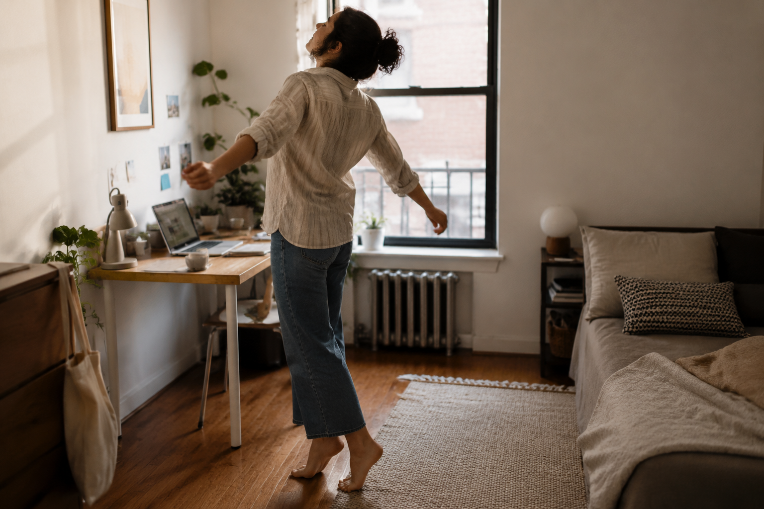 A person in a small apartment standing from a desk and moving gently in a narrow open space