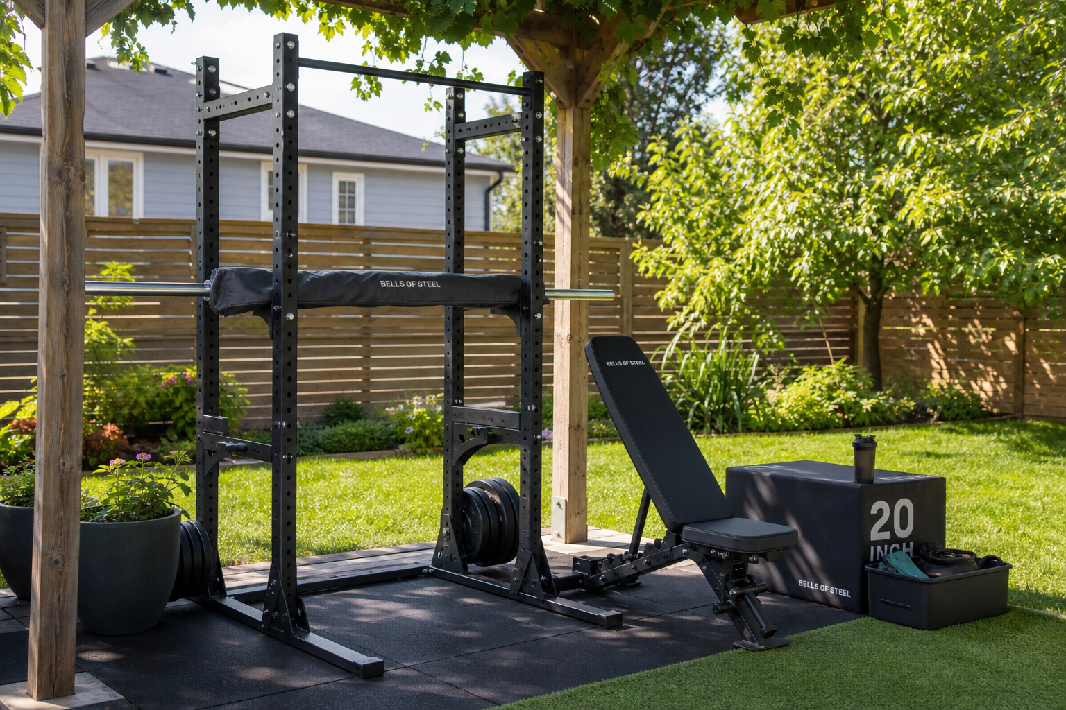 A residential backyard home gym setup with a powder-coated power tower, adjustable bench, and plyo box on rubber flooring under a pergola.