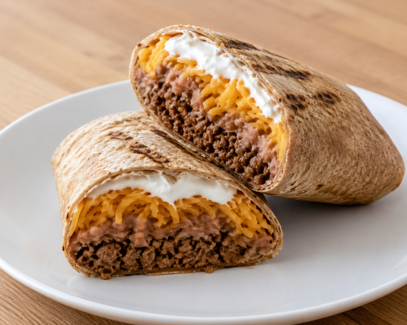 Homemade burrito cut open with seasoned lean ground beef, refried beans, cheddar, and Greek yogurt in a low-carb tortilla