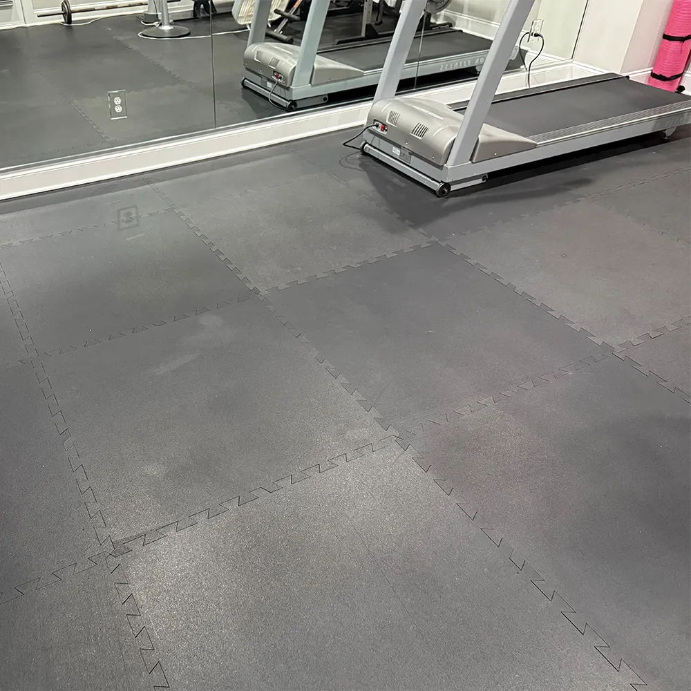 Black interlocking rubber floor tiles installed beneath a home treadmill