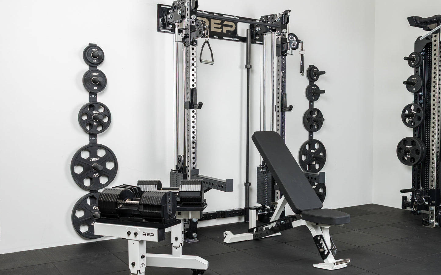 Compact home gym with power rack, loaded barbell, bench, plates, and dumbbells
