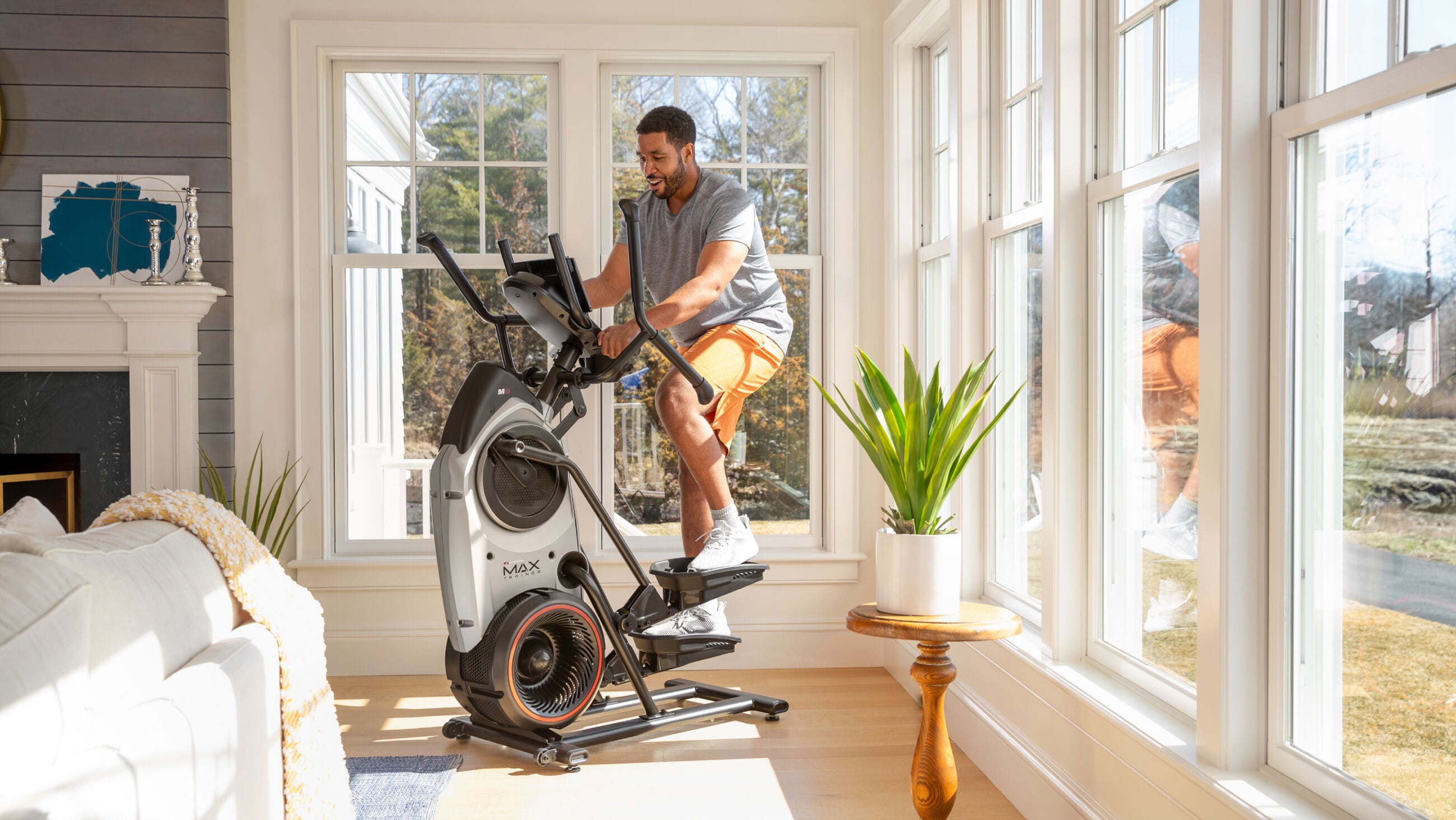 Bowflex Max Trainer M6 in a modern living room beside a window and armchair