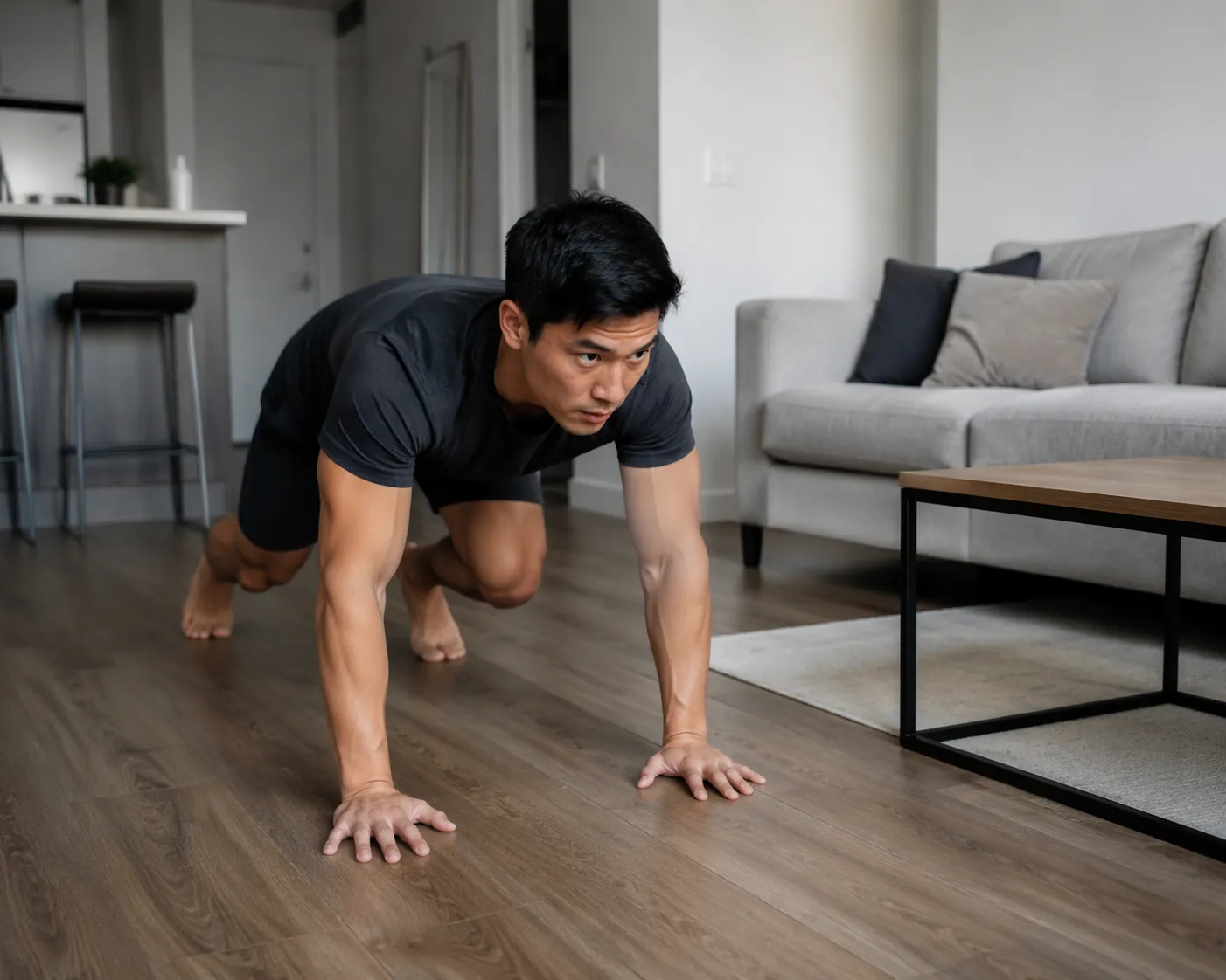 Person performing a bear crawl on a small apartment living room floor with a couch and coffee table nearby