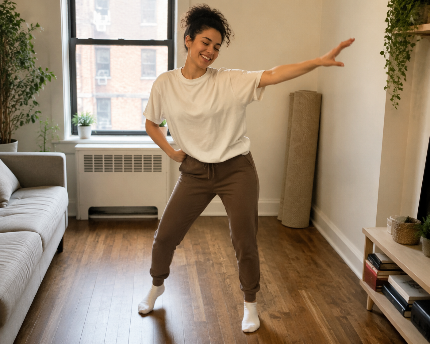 A person dancing in a cleared apartment living room with warm natural light