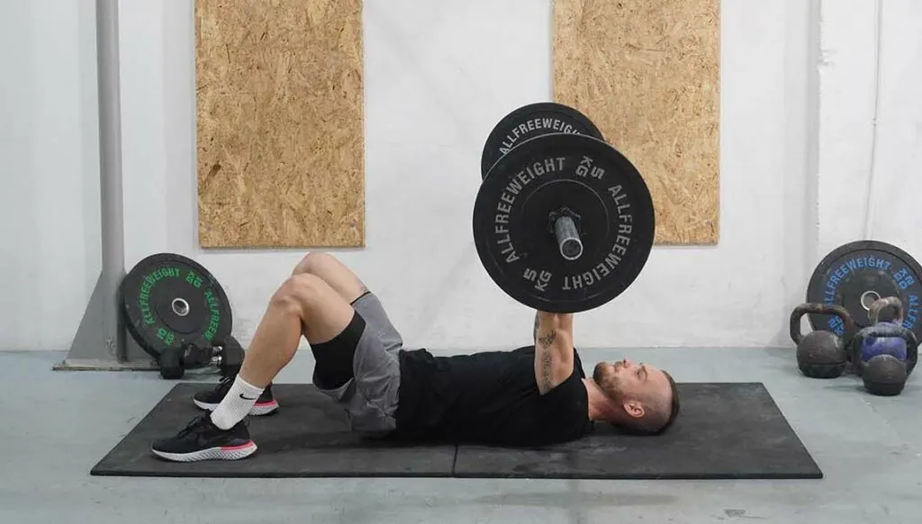 Lifter performing a barbell floor press on a padded floor