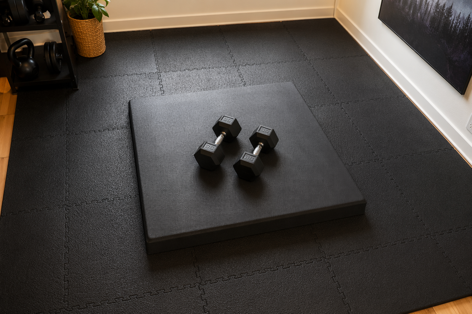 Apartment gym floor with black interlocking rubber tiles and a thick crash pad under dumbbells