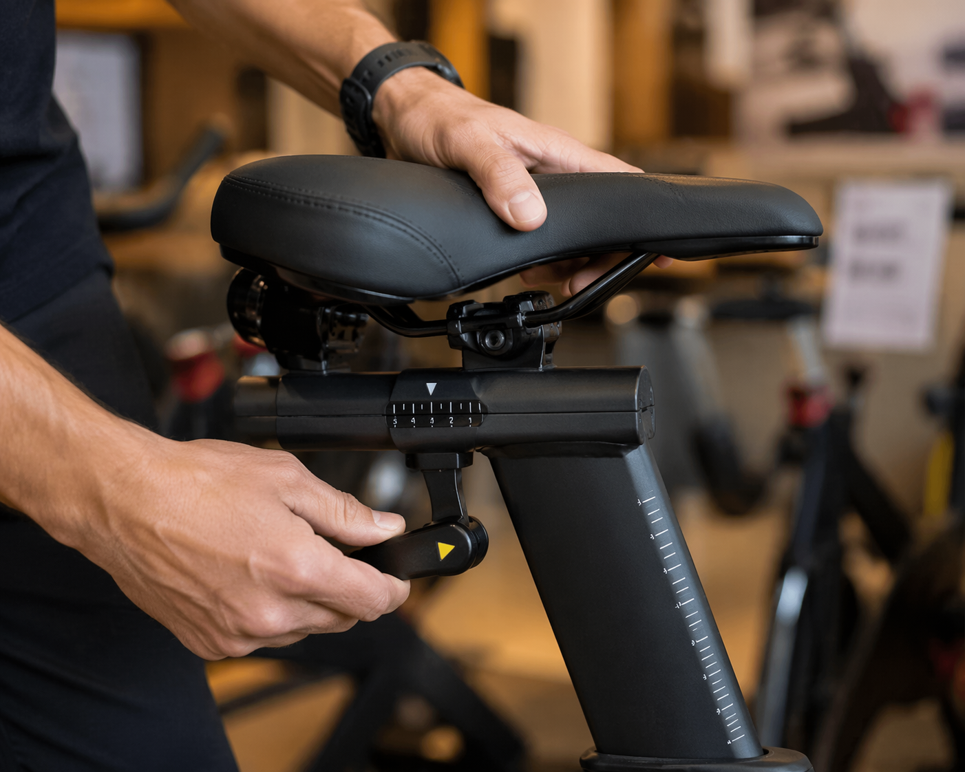 Hands adjusting the seat and handlebar settings on showroom exercise equipment